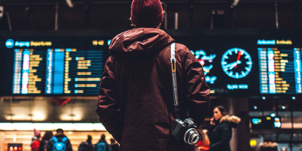 Persona en un aeropuerto mirando las pantallas con los próximos vuelos. 